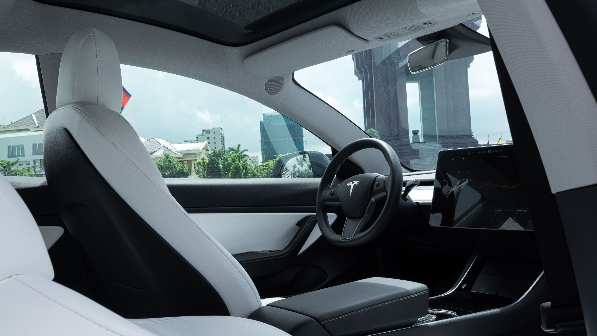 Luxurious interior of a modern electric car with white leather seats and advanced dashboard features.