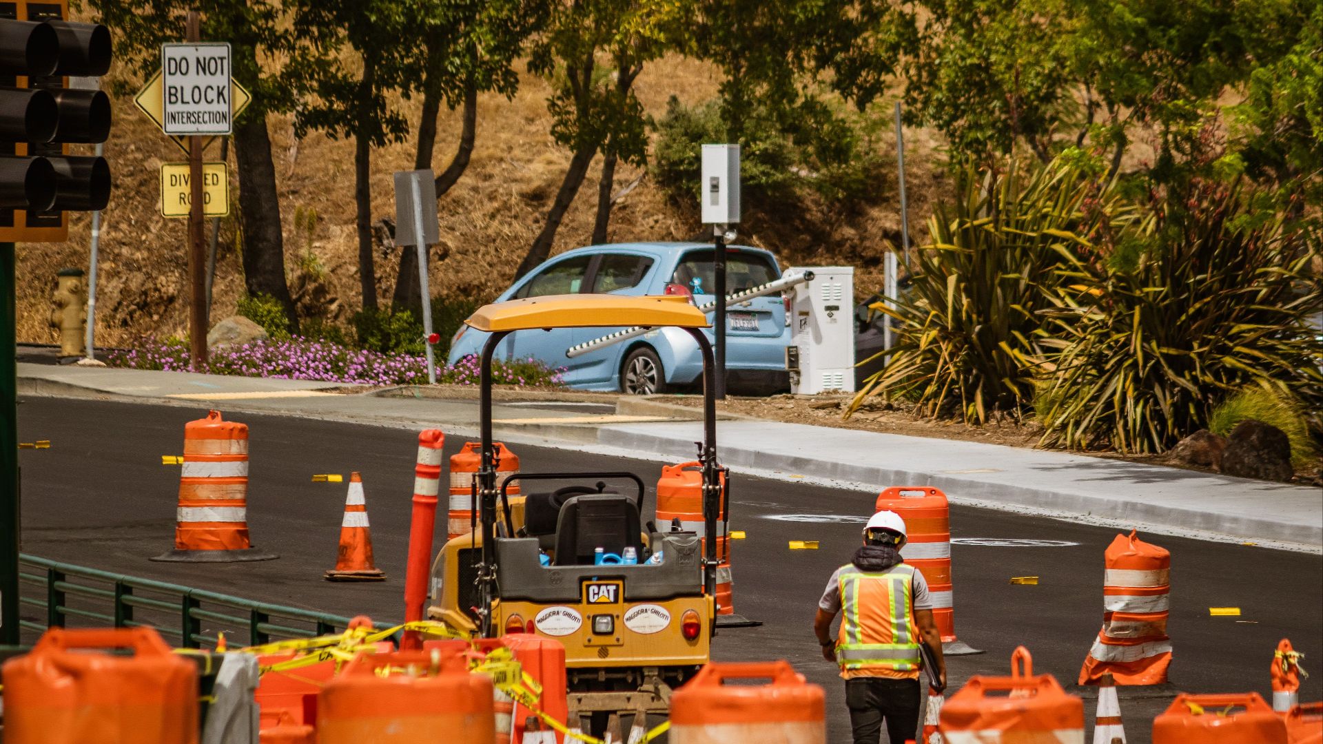 A road construction worker surrounded by safety cones on a street in daylight.