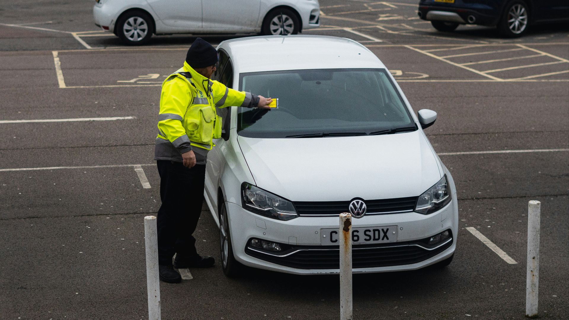 man in yellow jacket standing beside white car