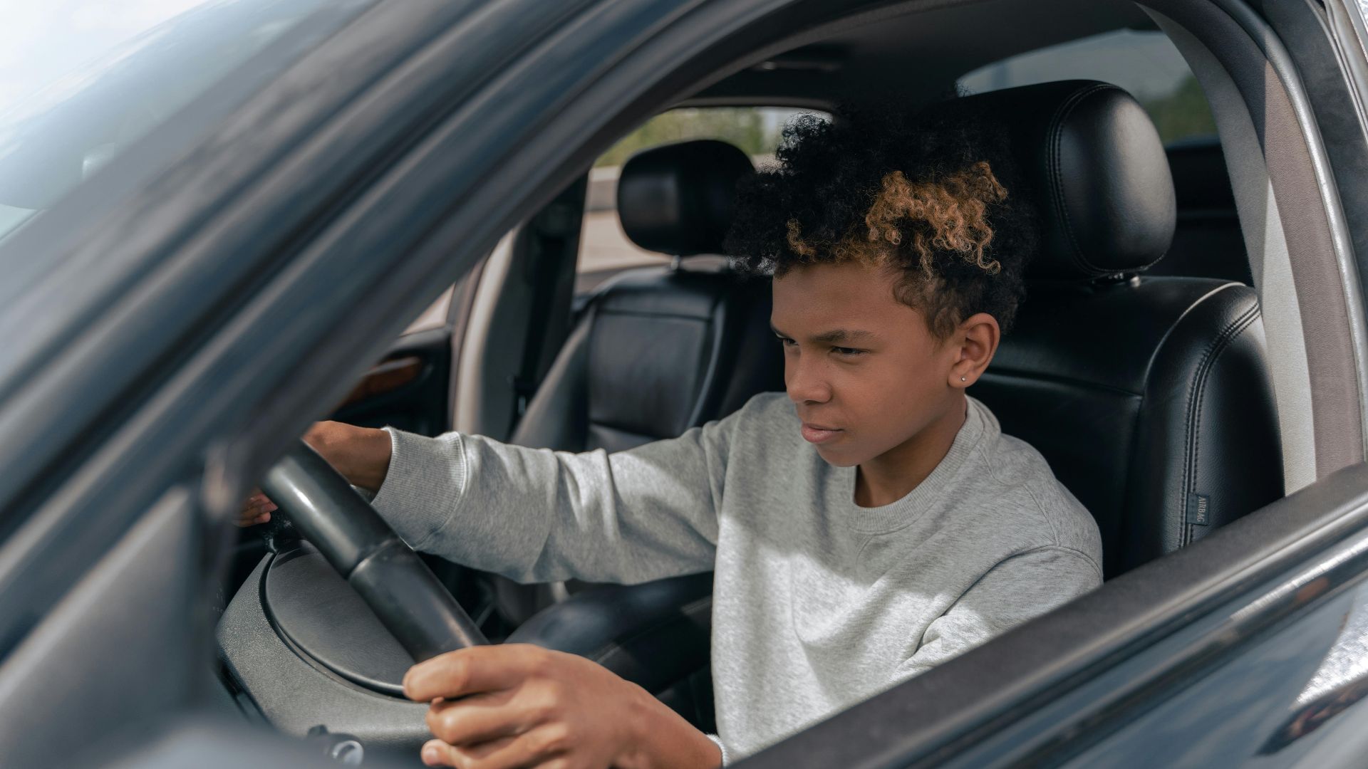 Teen boy learning to drive a car with focus and determination.