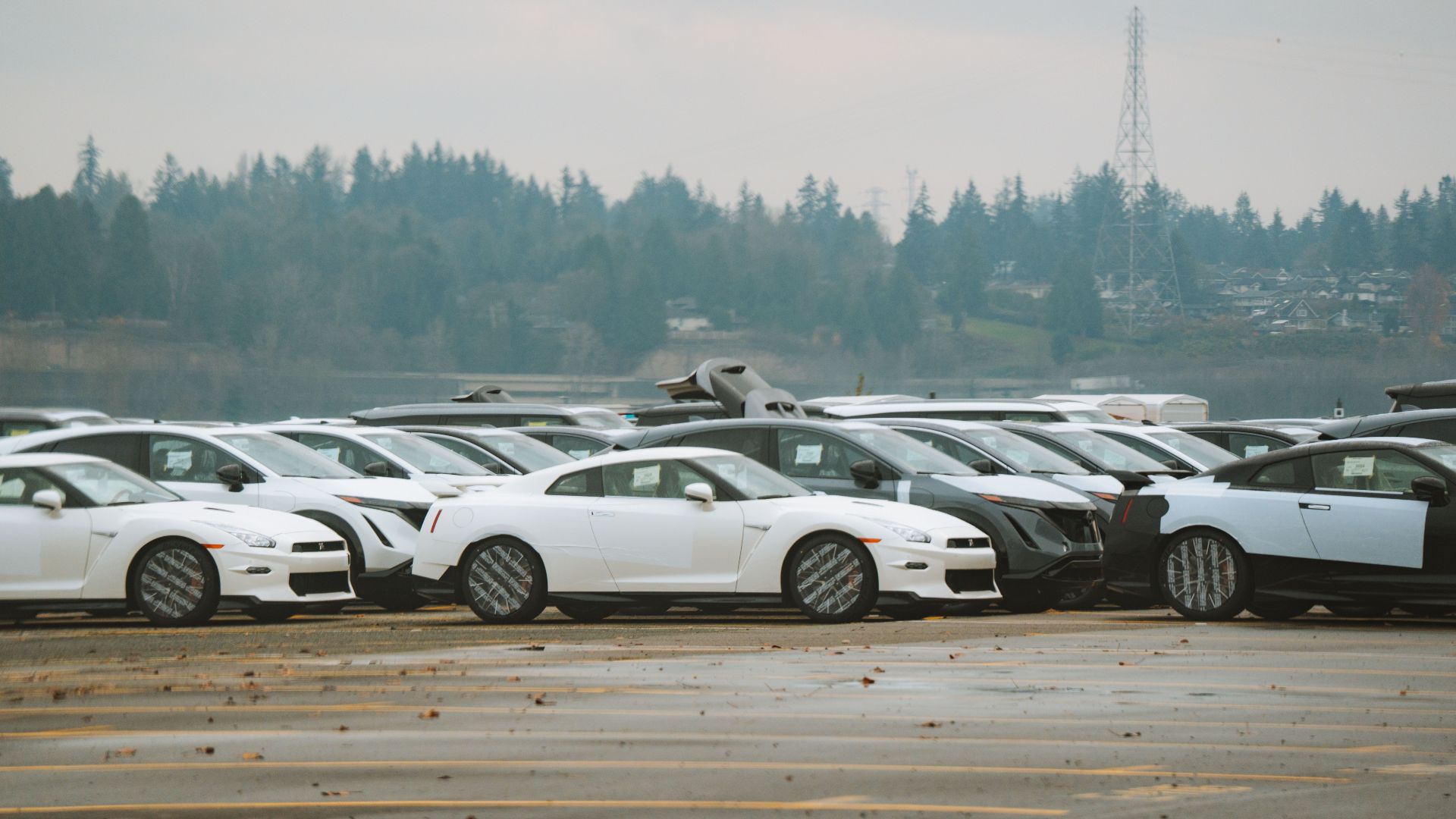 Wide shot of multiple sports cars parked outdoors on a cloudy day.