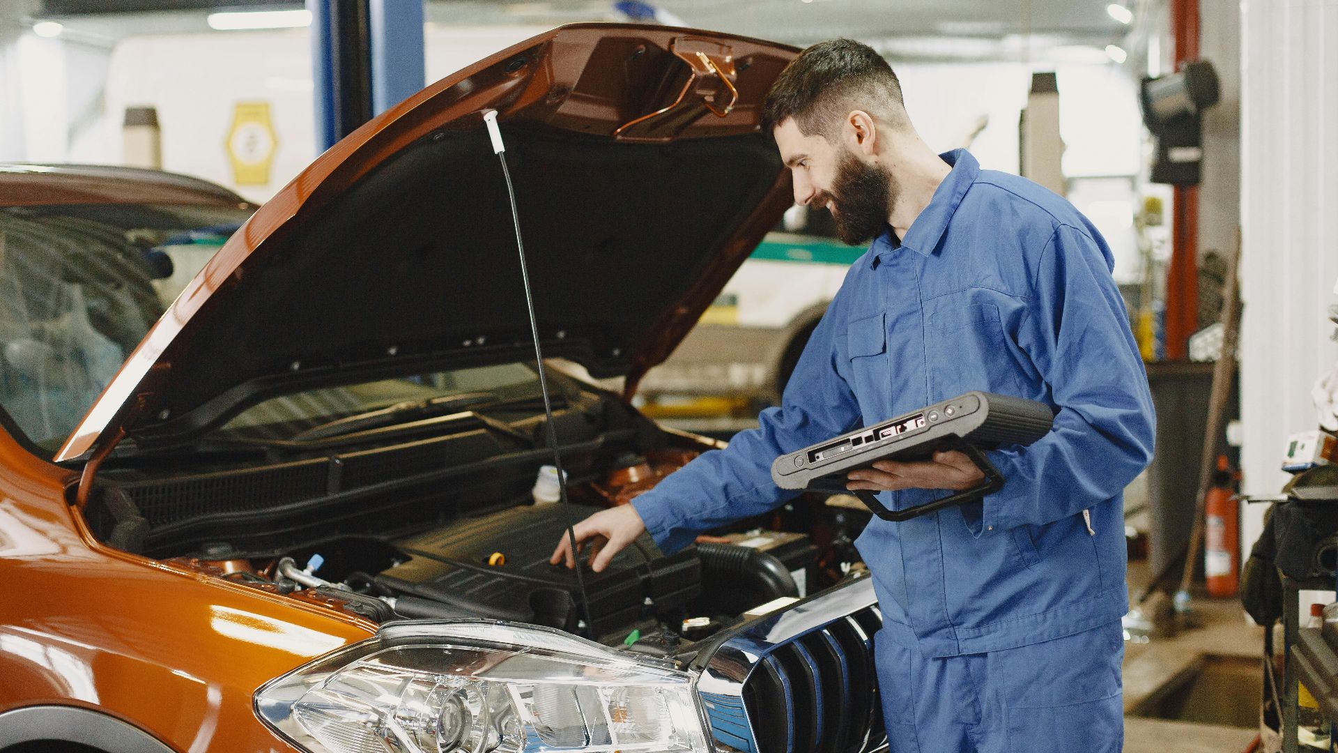 Skilled mechanic working on car engine diagnostics in a modern garage.