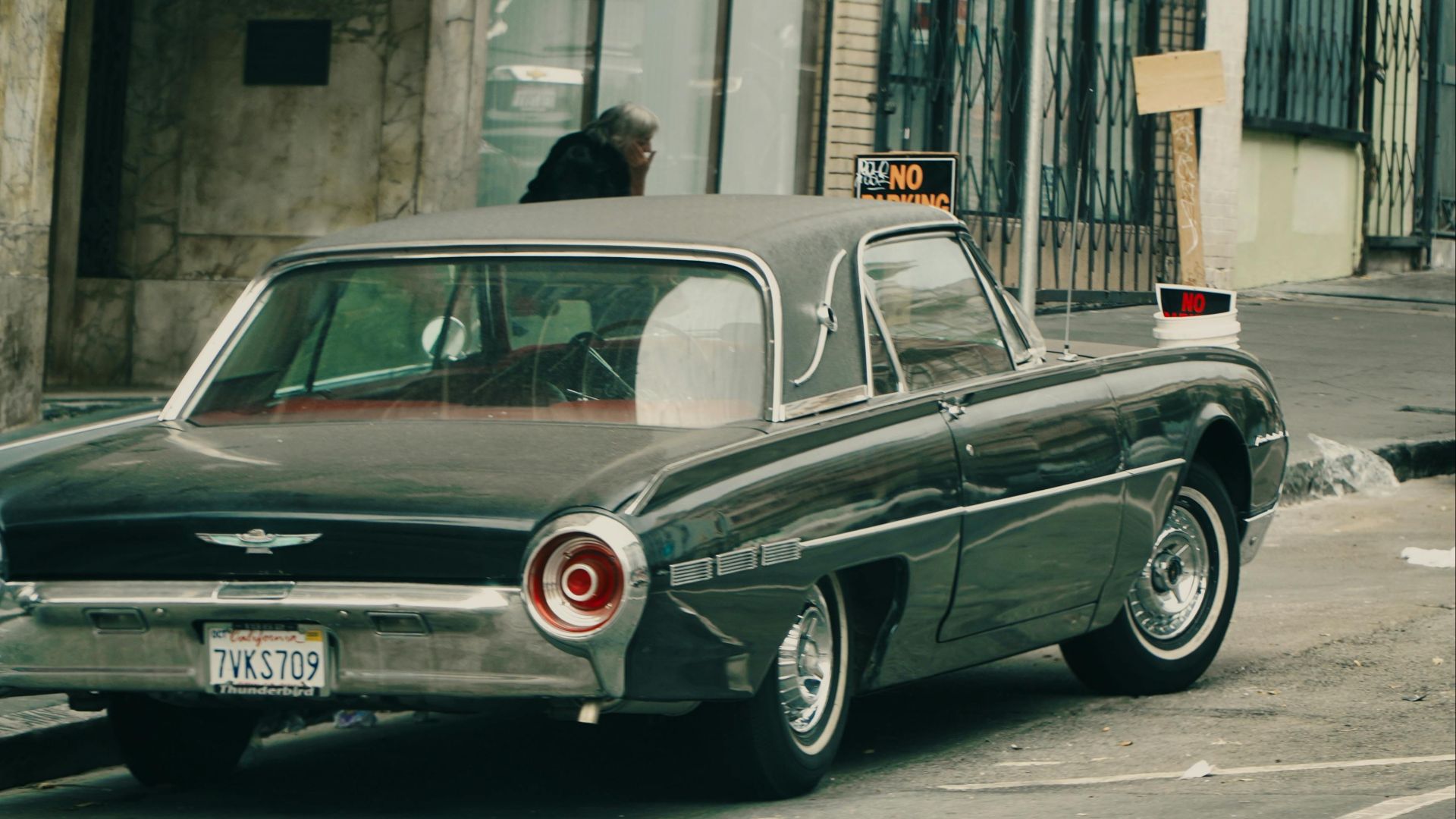 Vintage Ford Thunderbird parked on a city street with urban backdrop.