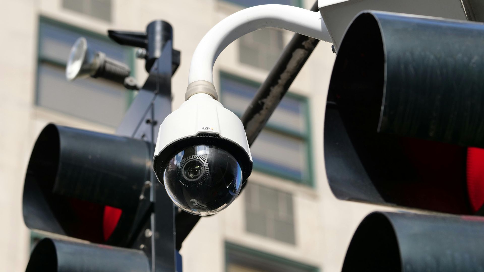 Close-up of a modern dome security camera monitoring an urban street.