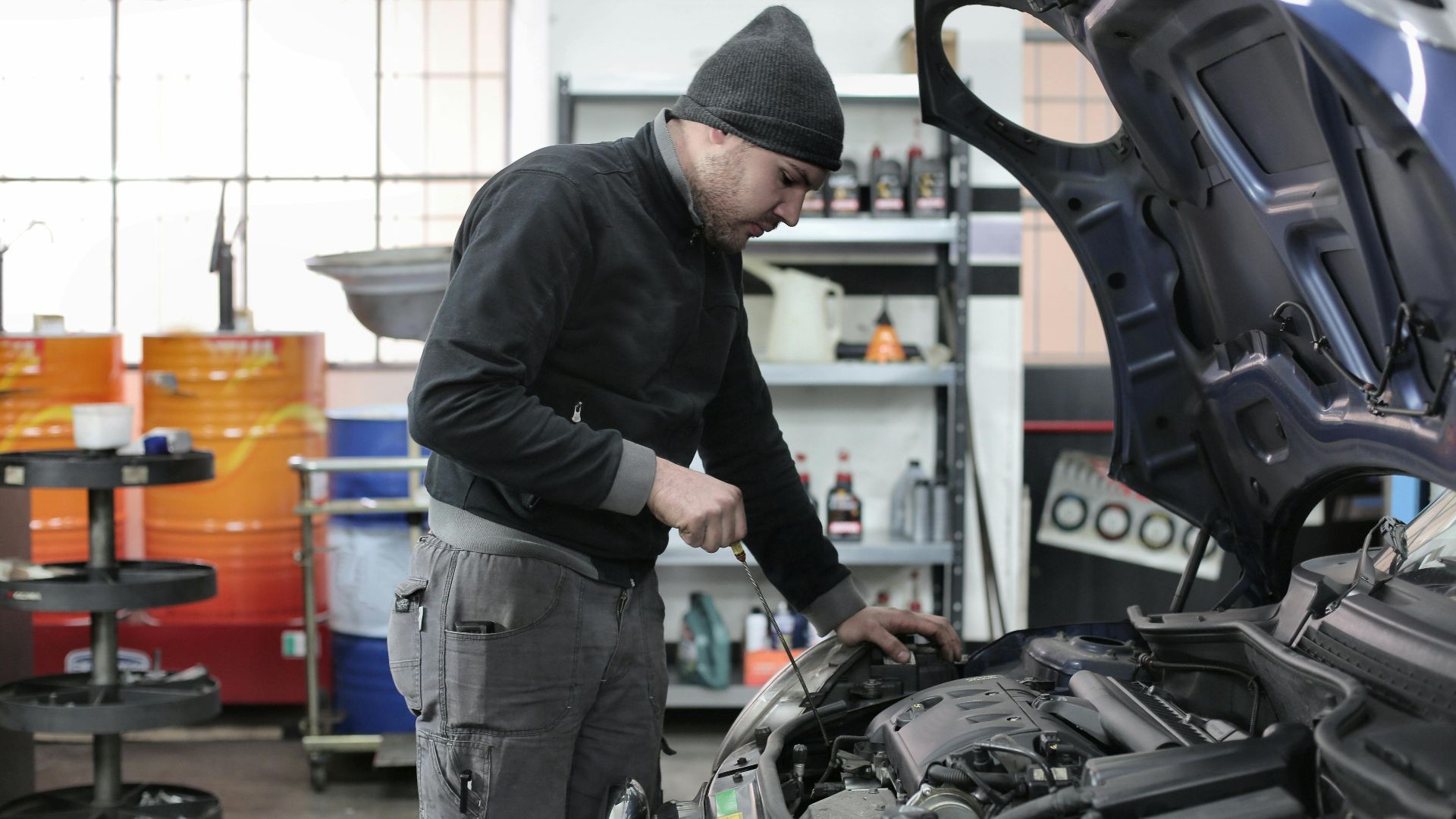 Mechanic checking a car engine in a garage, ensuring quality maintenance and repair.