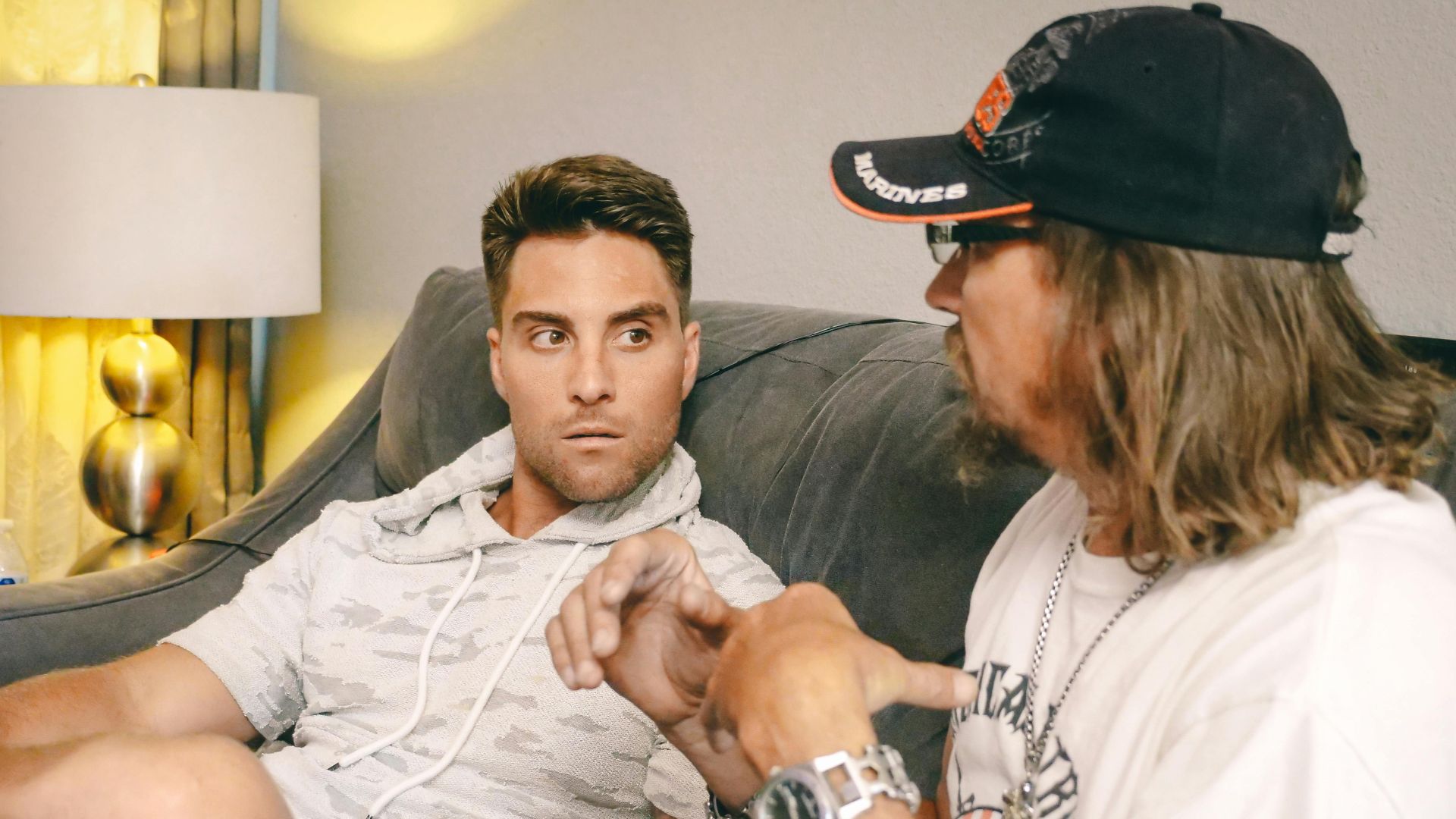 Two men having an intense discussion on a couch indoors, focused on one another.