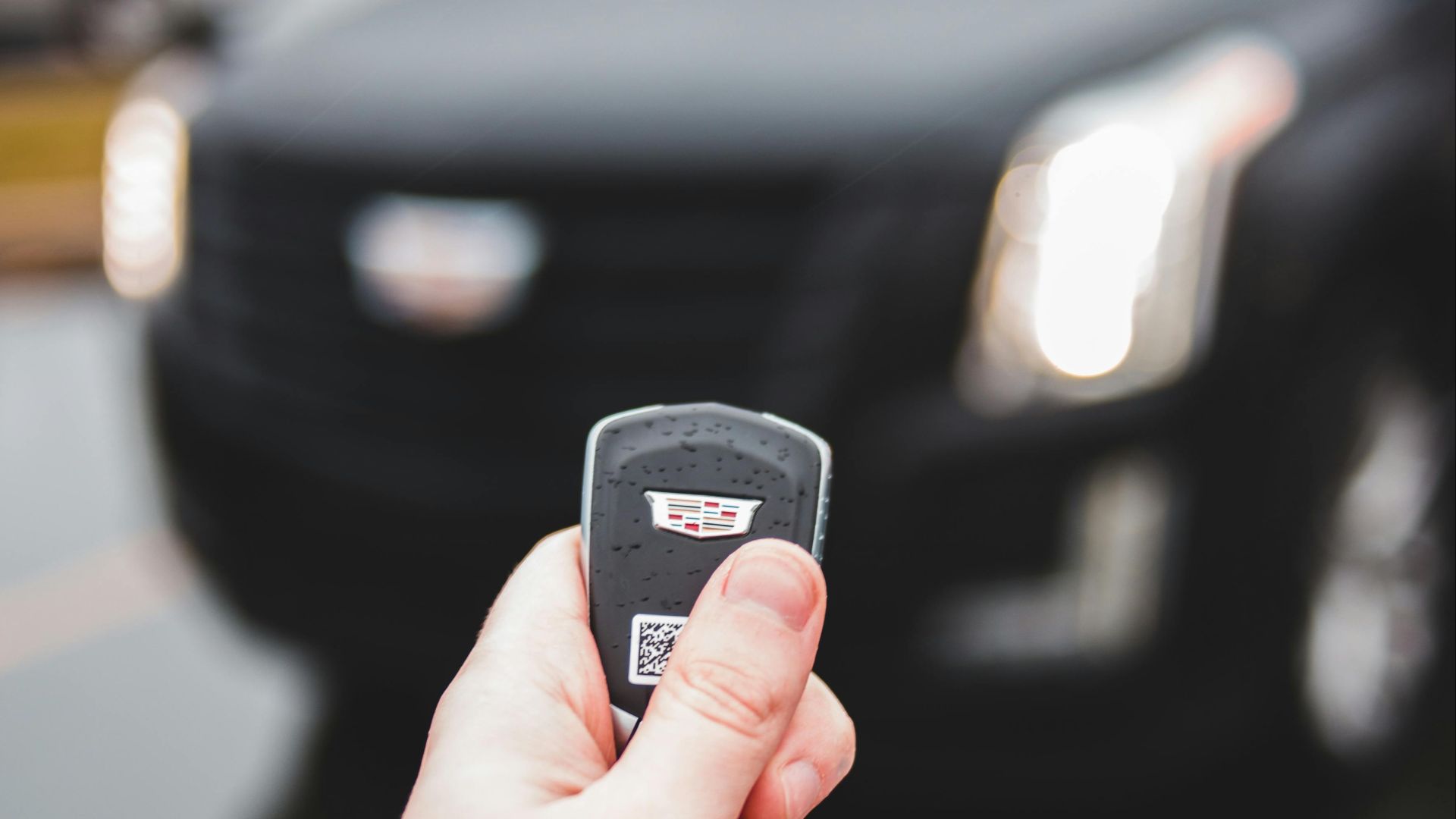 Blurred SUV background with person holding a car key, outdoor setting.