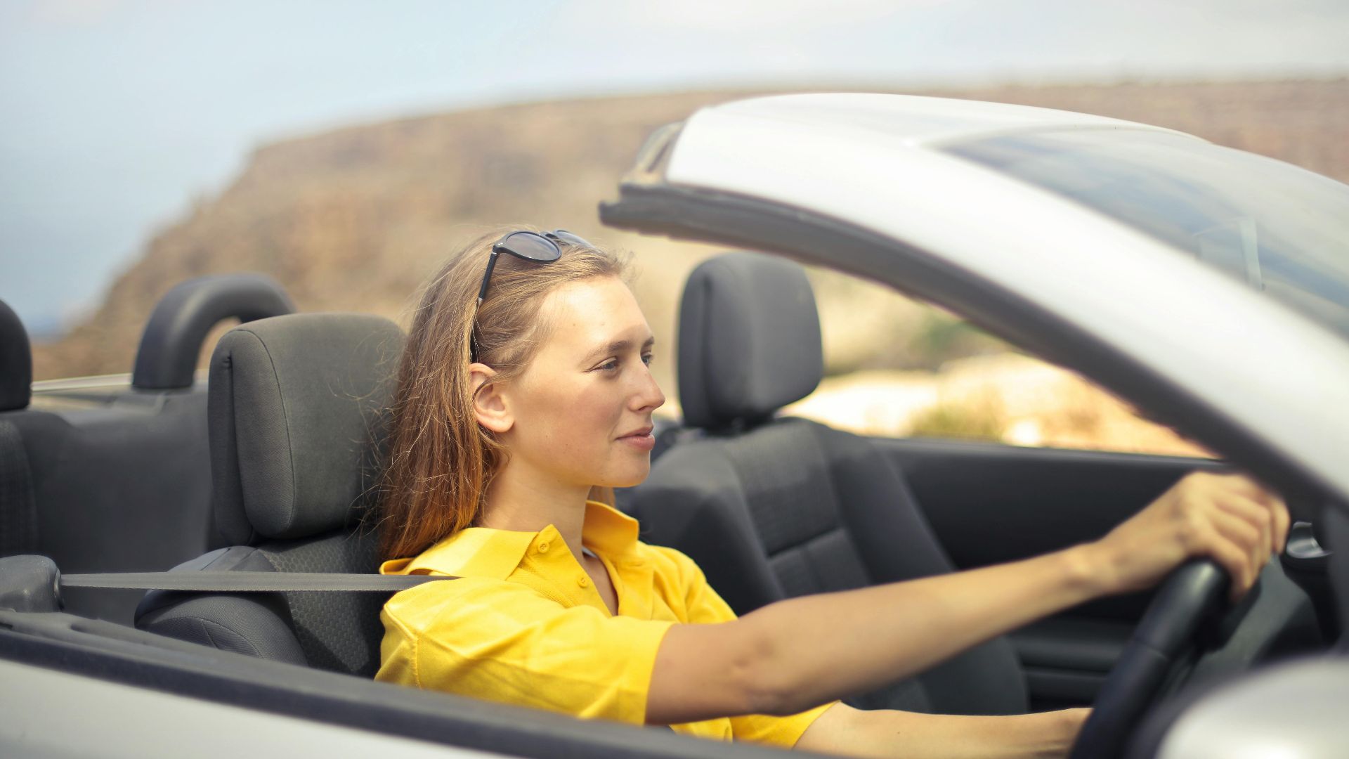 A young woman enjoys driving a convertible on a sunny day in Malta.