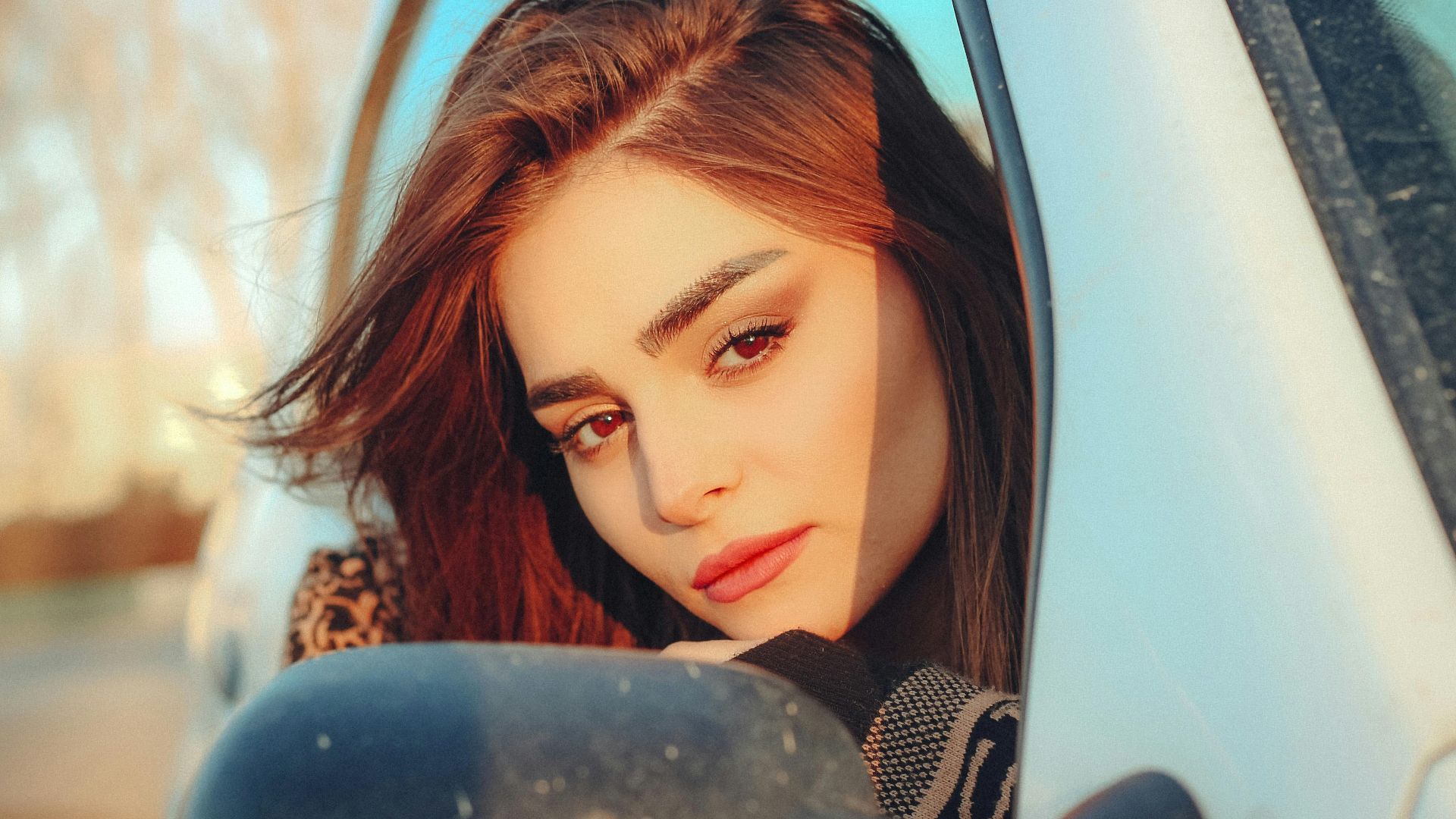 Young woman gazing through car window in Tehran with thoughtful expression.
