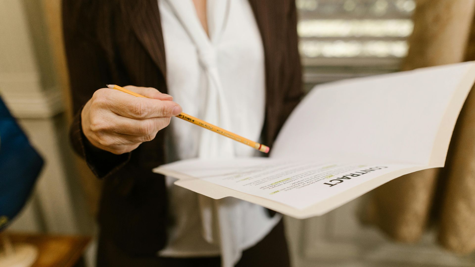 A businesswoman holds a contract, pointing with a pencil. Legal and corporate setting.