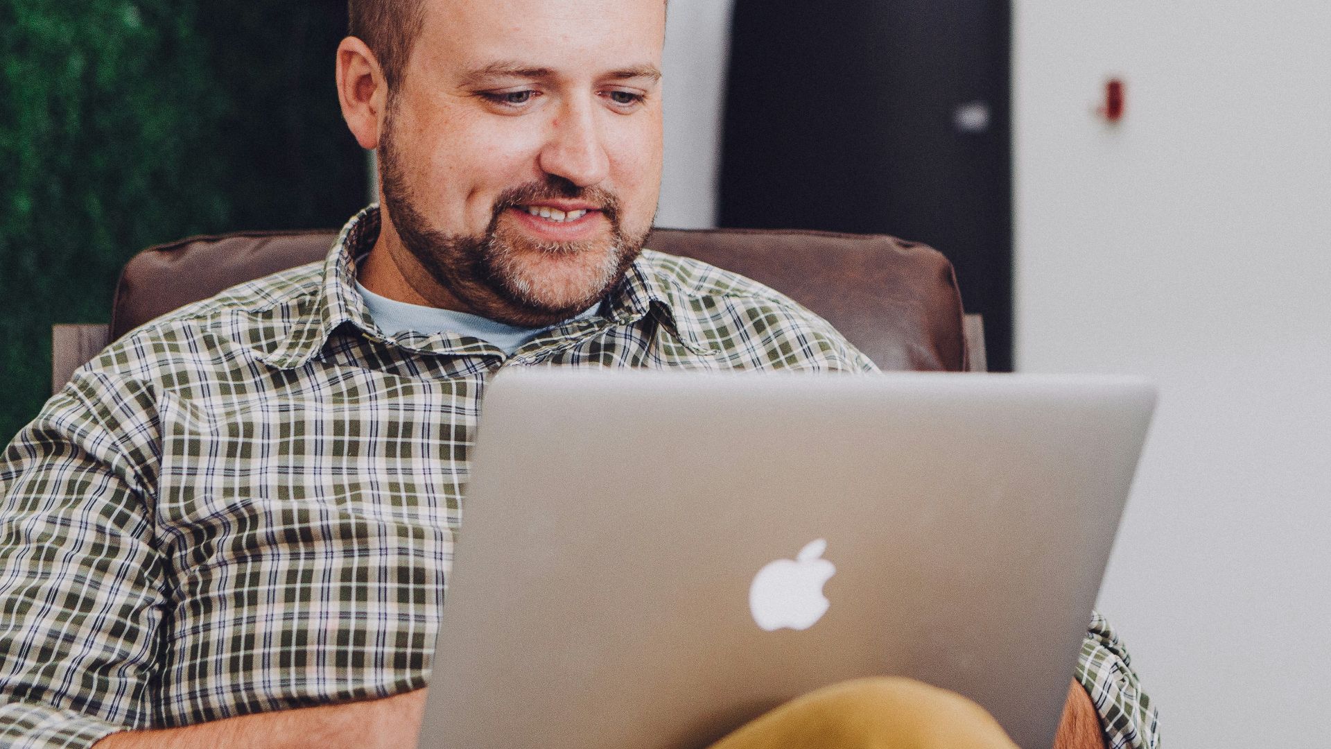 man smiling and using MacBook