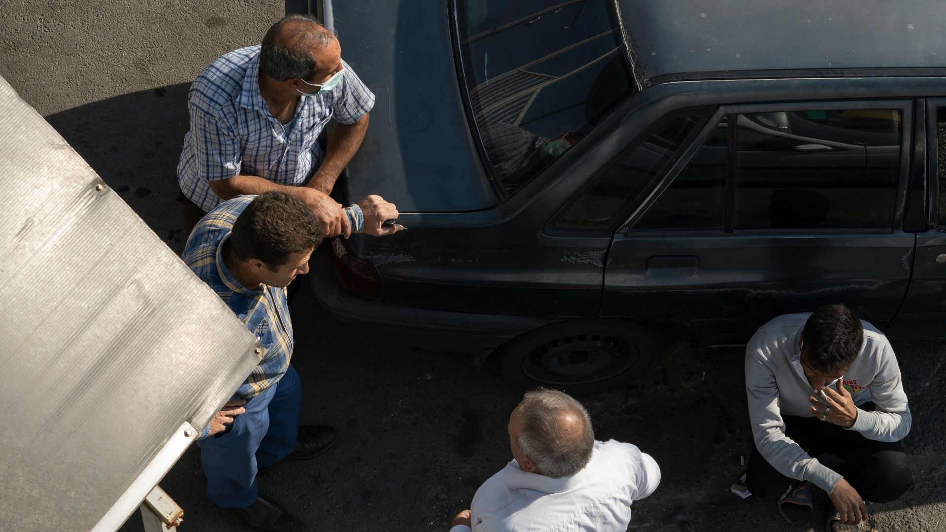 a group of men standing around a car