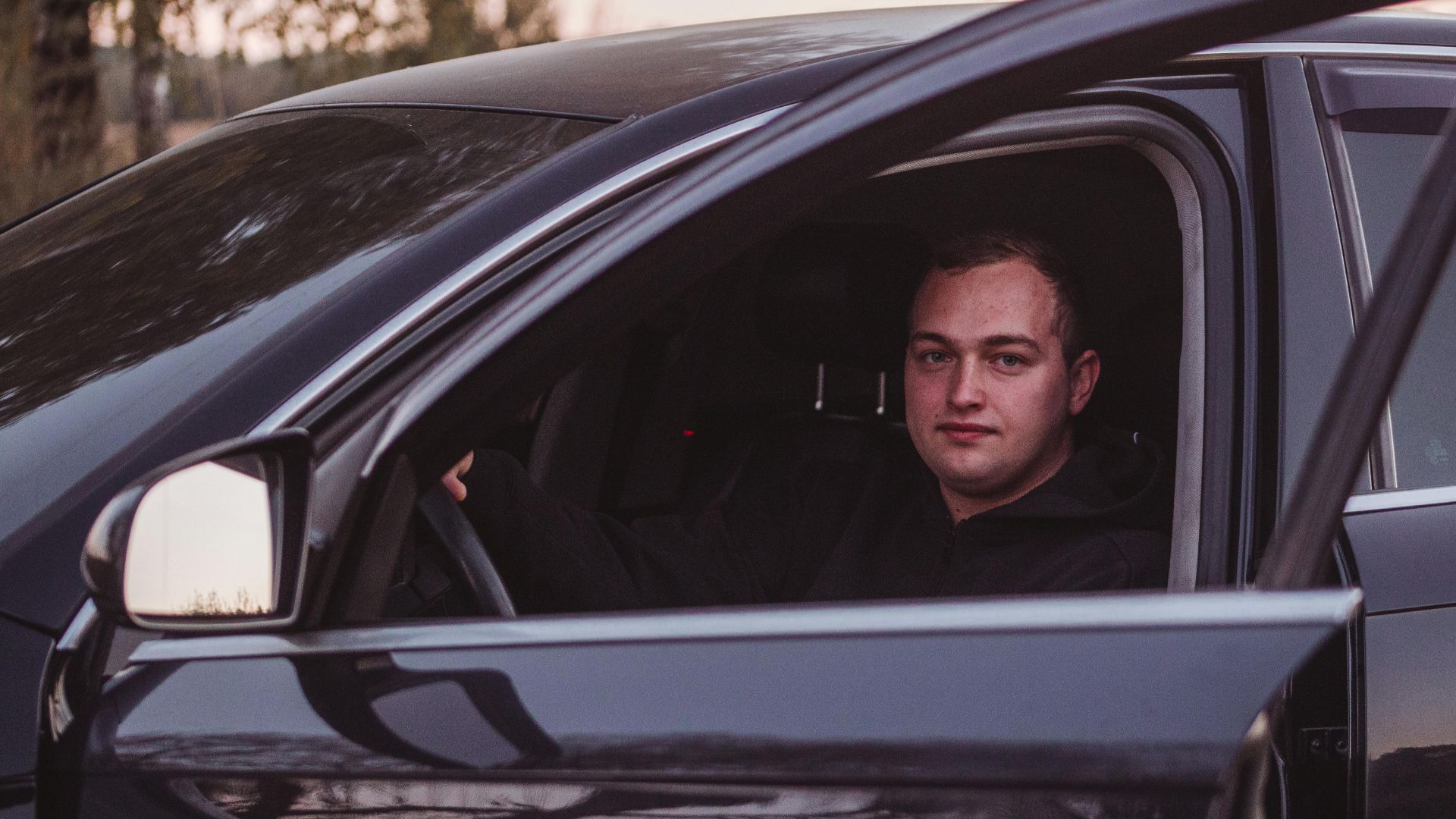 Male driver in a parked car during twilight, capturing a serene moment.
