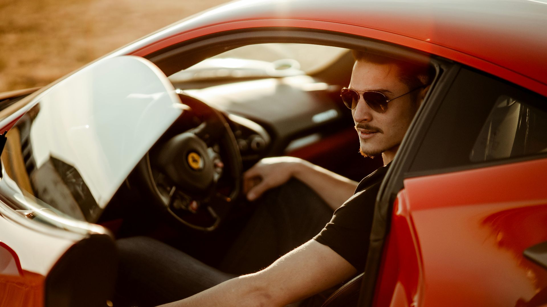 A stylish man sitting in a luxurious red sports car, enjoying the sunlight.