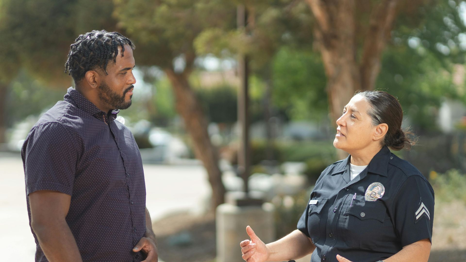 A police officer engaging warmly with a community member outdoors on a sunny day.