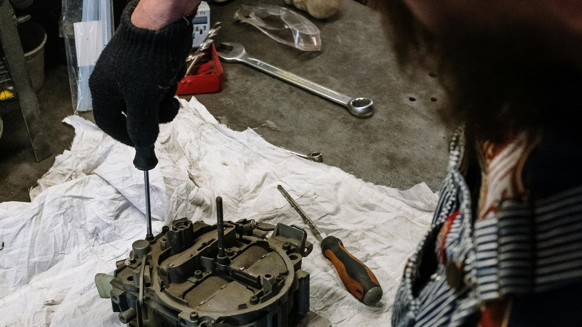 Mechanic at work fixing engine component in garage environment.