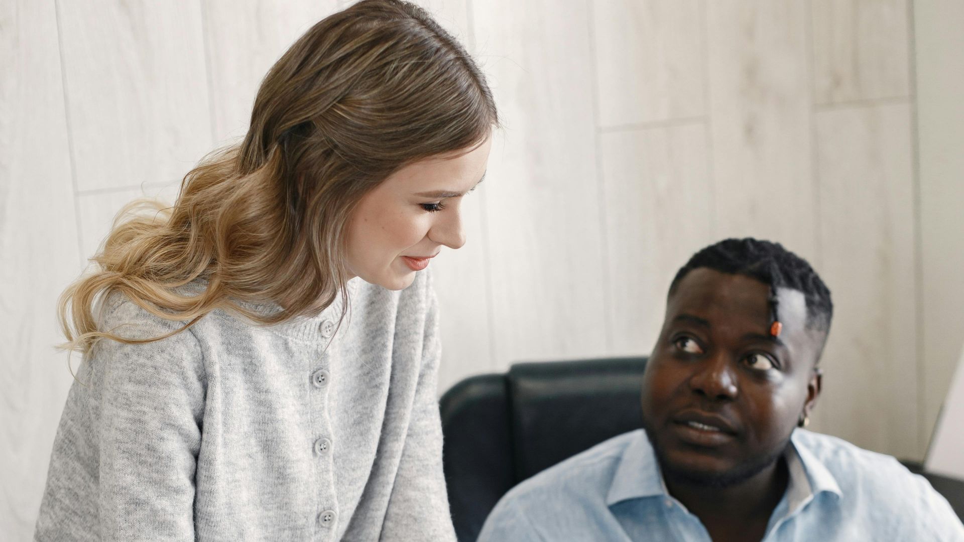 Two professionals discussing work in an office environment, promoting teamwork and diversity.