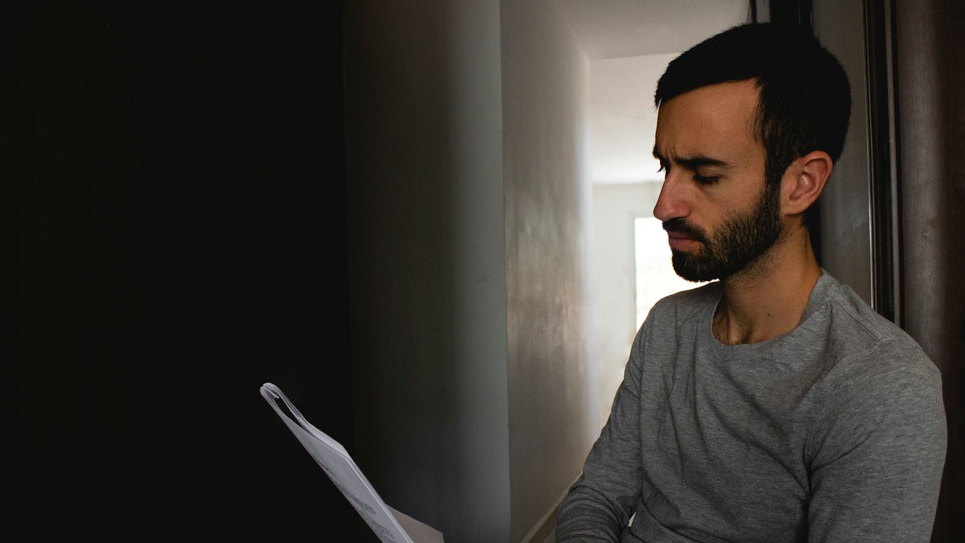 man in gray crew neck shirt holding white printer paper