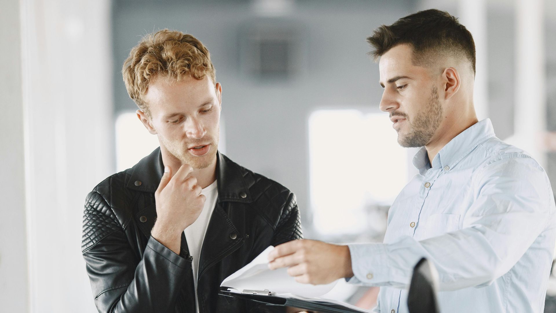 Two adults discussing purchasing options at a motorcycle dealership.