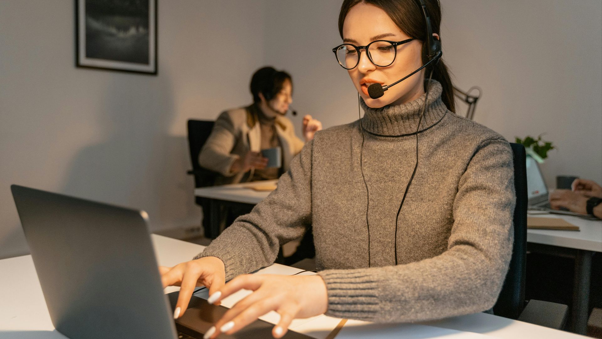 Two call center agents providing customer service in a modern office environment.