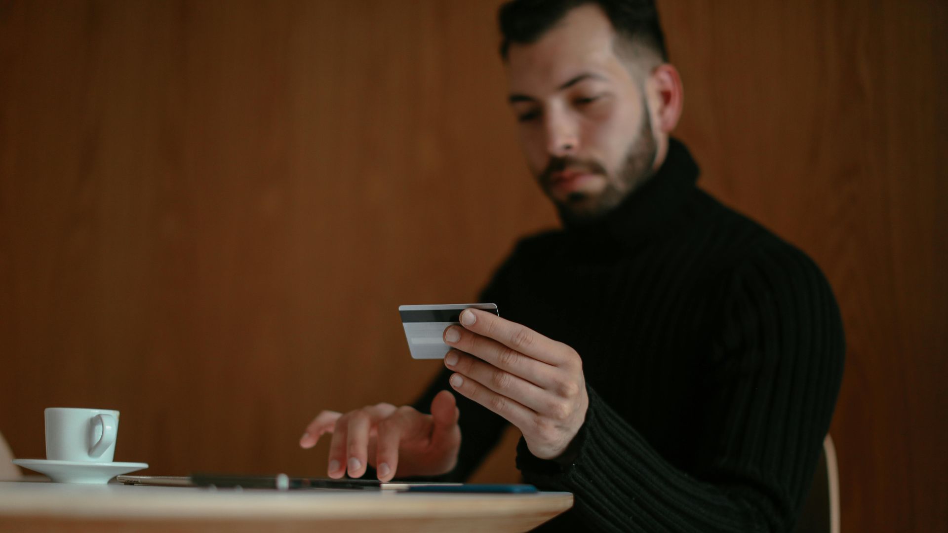 Focused man in café using tablet and credit card for online shopping.