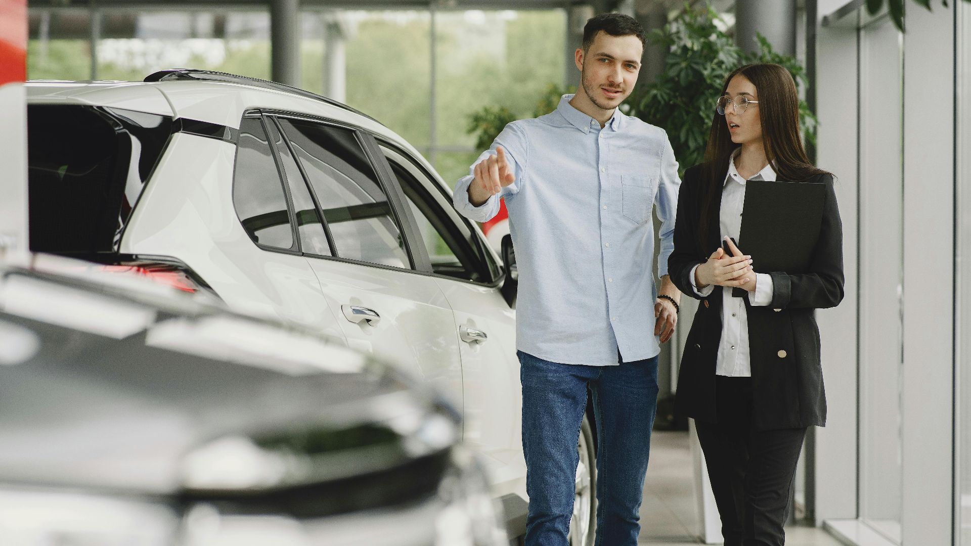 Customer and salesperson discussing a vehicle inside a modern car dealership showroom.