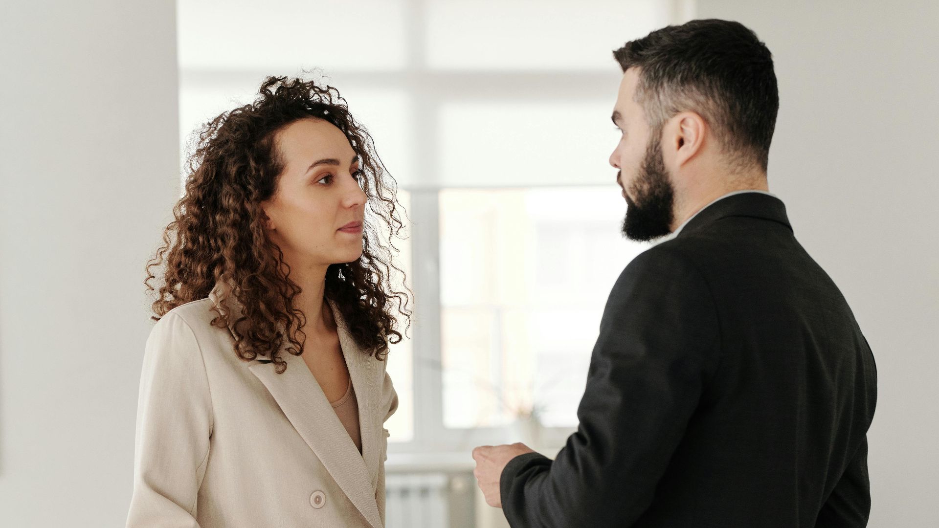Two professionals engaged in a discussion in a bright, modern office setting.