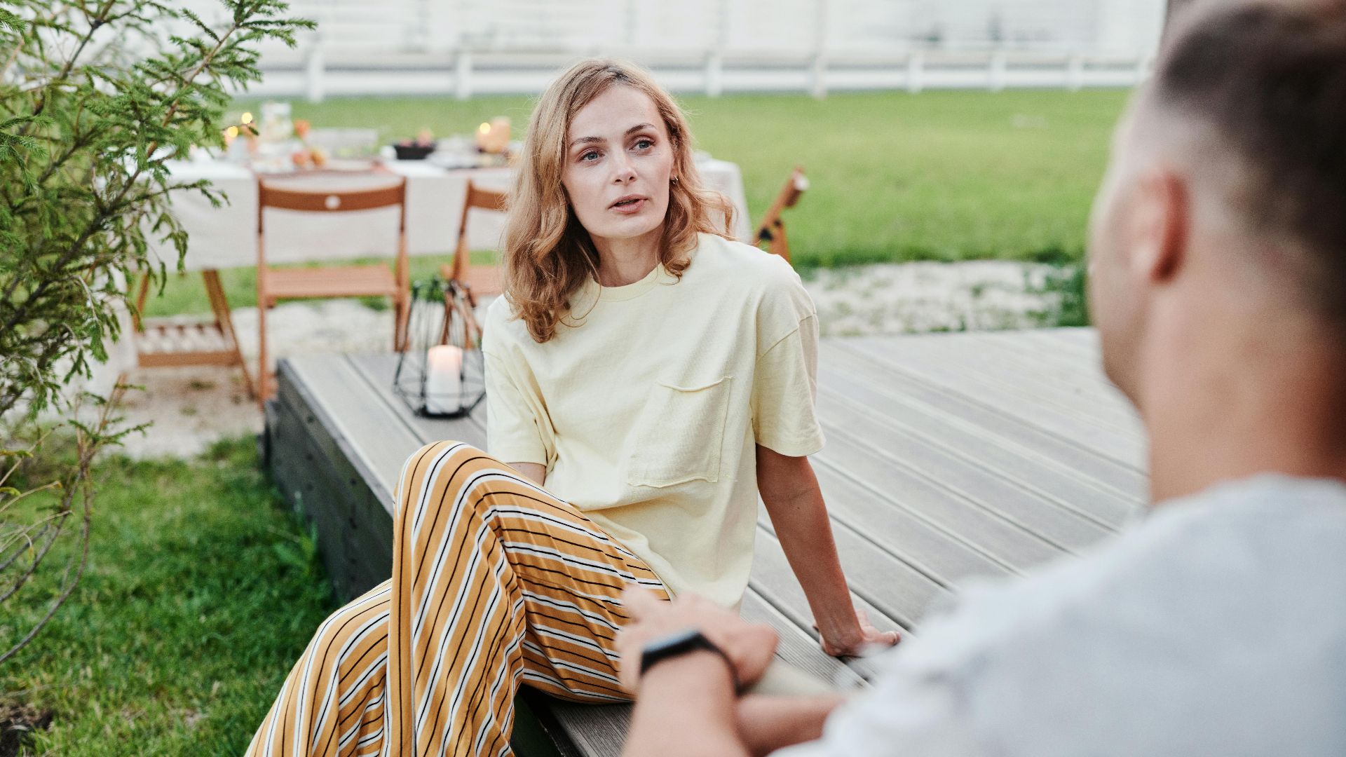 A couple engaged in a thoughtful conversation outdoors in a relaxed garden setting.
