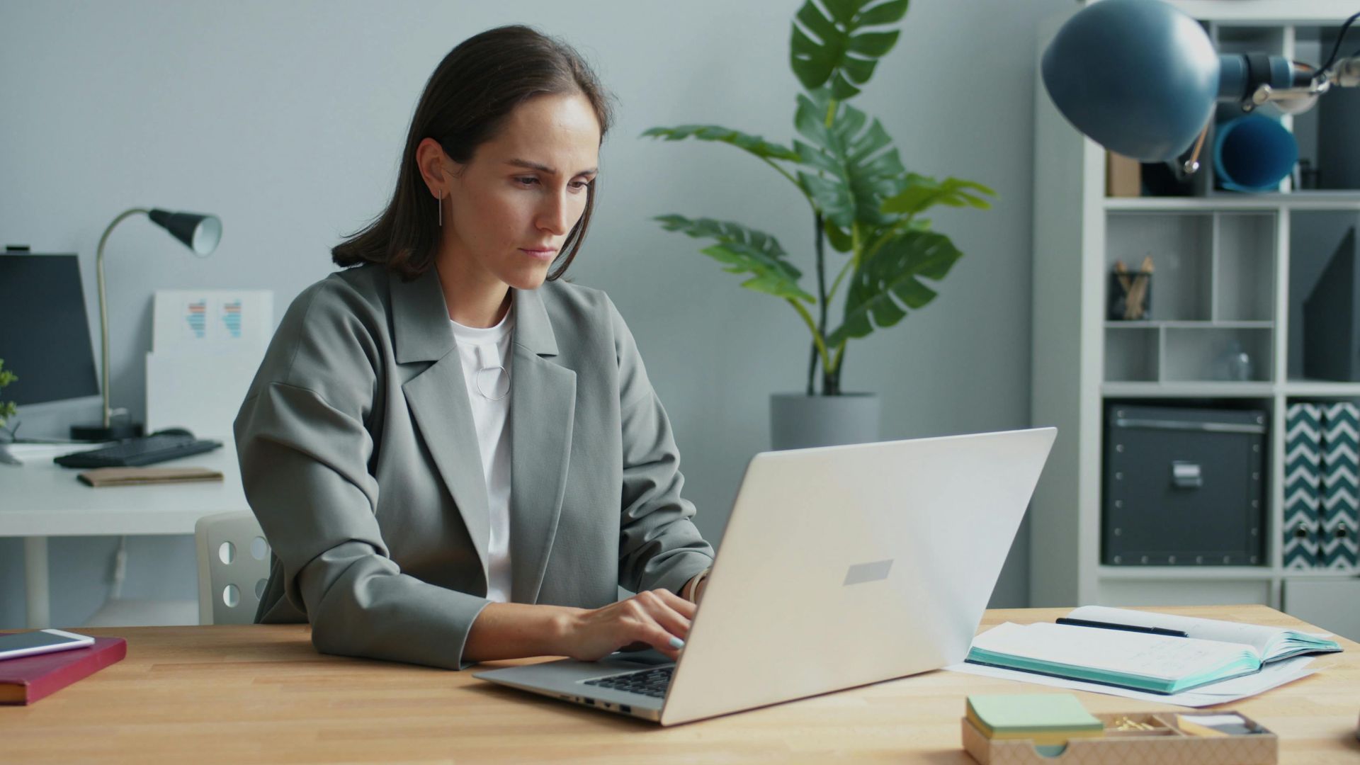 Businesswoman focused on laptop in modern home office setting.