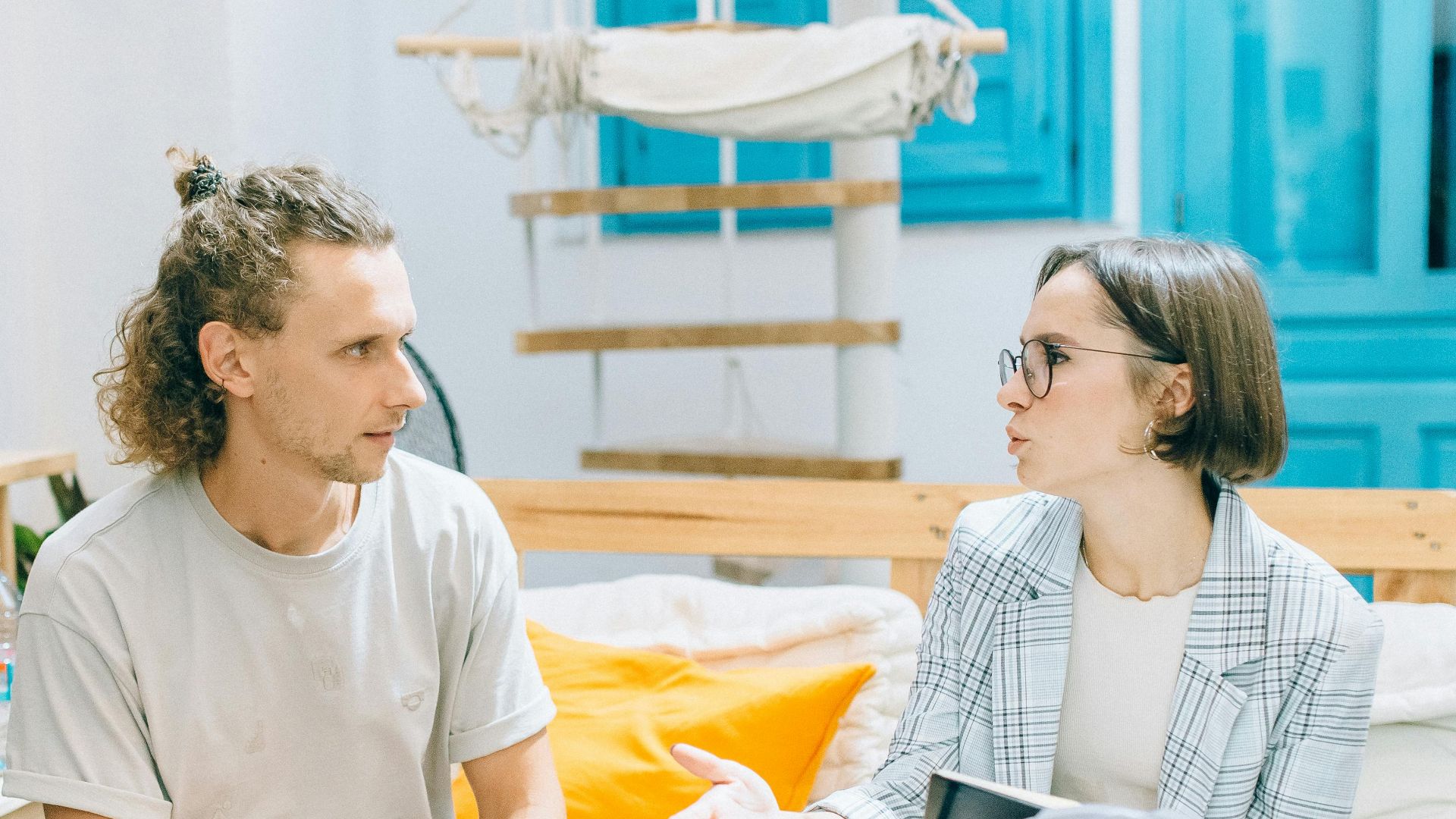 A man and woman discussing work in a stylish, bright living room setting.