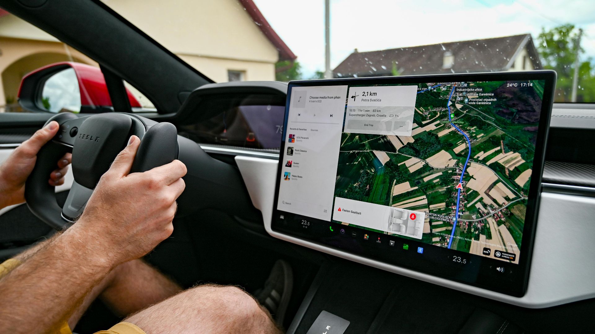 Man driving Tesla using GPS on touchscreen dashboard for navigation.