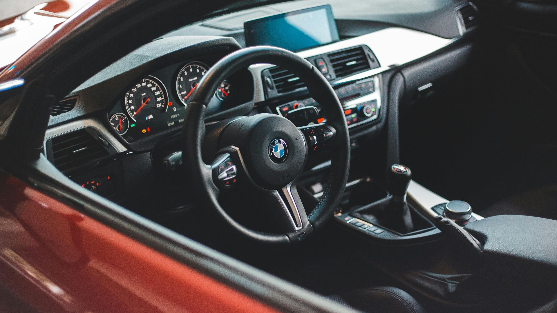 Comfortable cabin with modern steering wheel and panel in red car through opened window