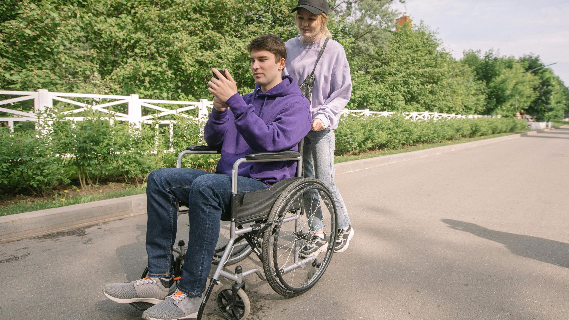 A happy couple enjoying a sunny day outdoors with a man in a wheelchair.