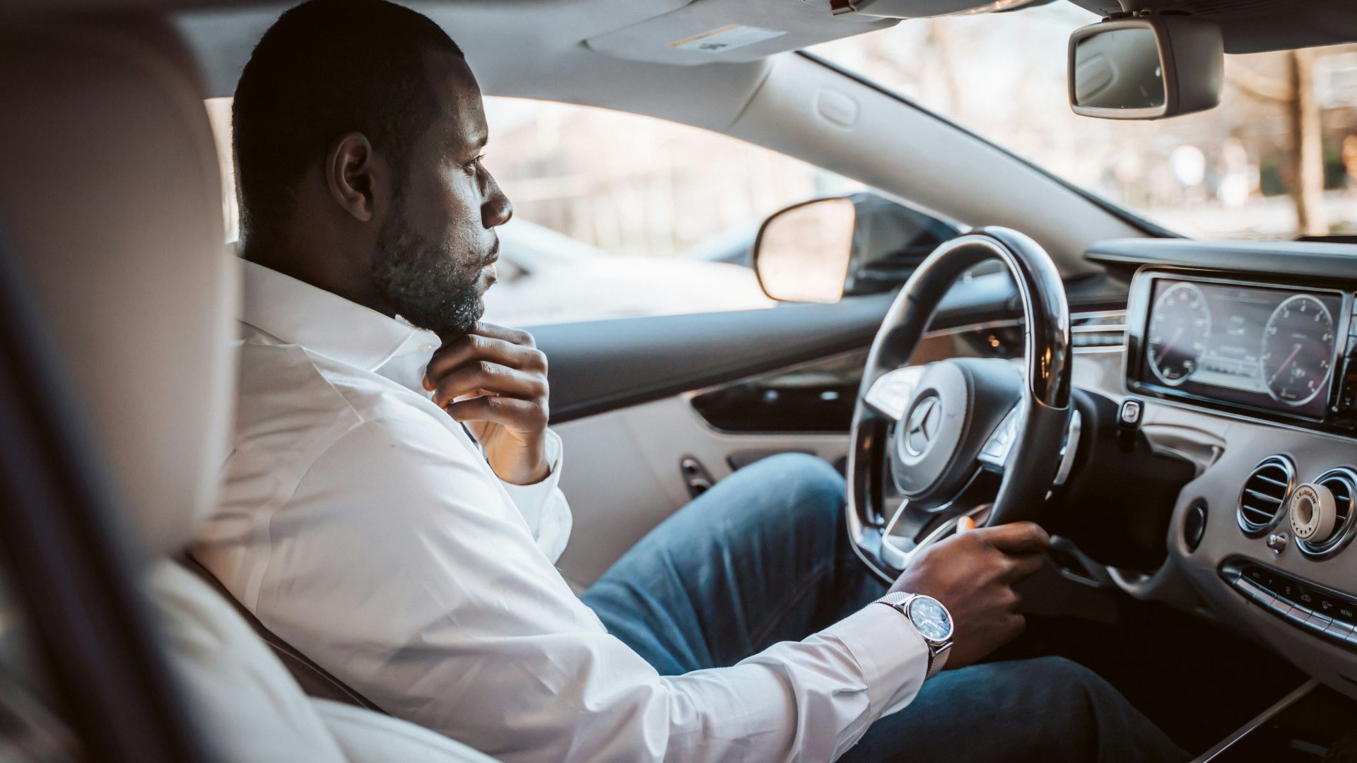 man in white dress shirt driving car during daytime