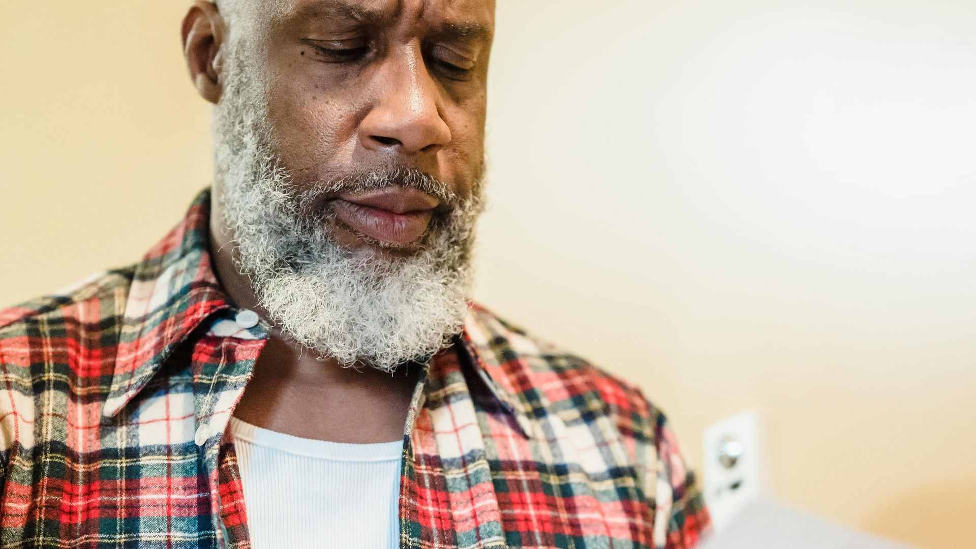 A mature man with a beard attentively reading documents indoors in a focused manner.