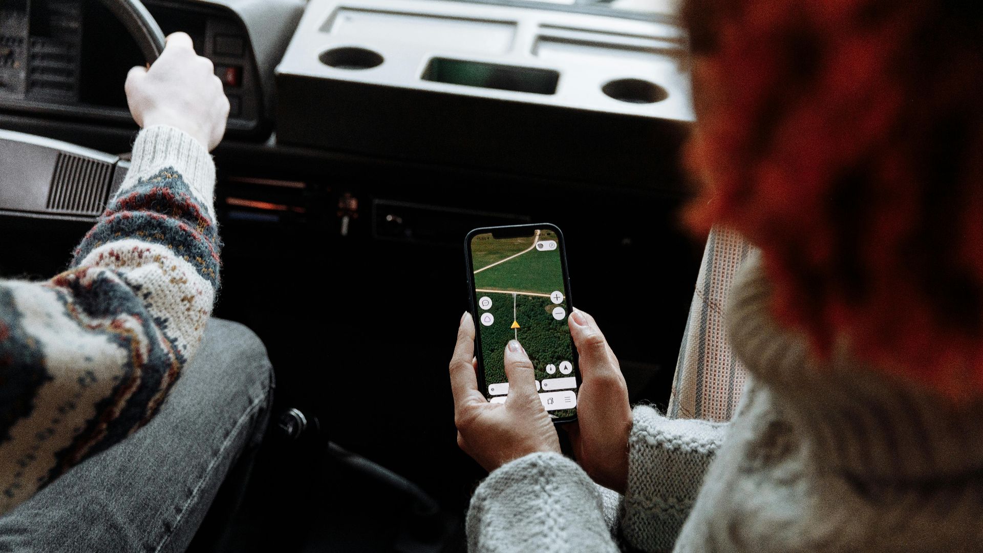 Two people using a navigation app on a smartphone during a road trip