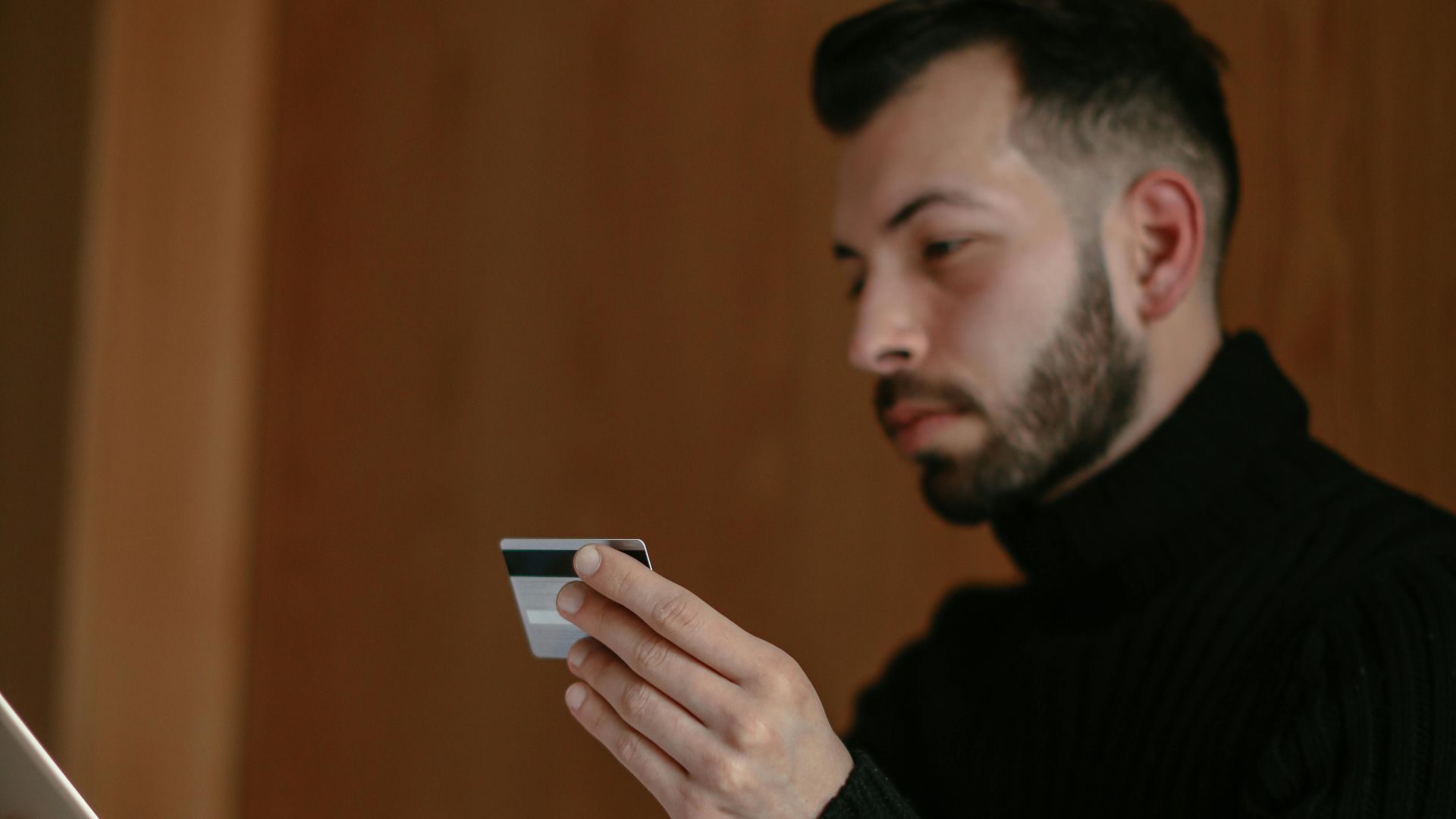 Bearded adult man using a tablet and credit card for online shopping at home.
