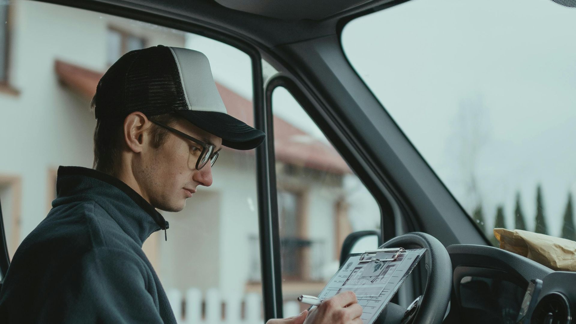 Delivery driver checks clipboard in van, preparing packages for delivery.