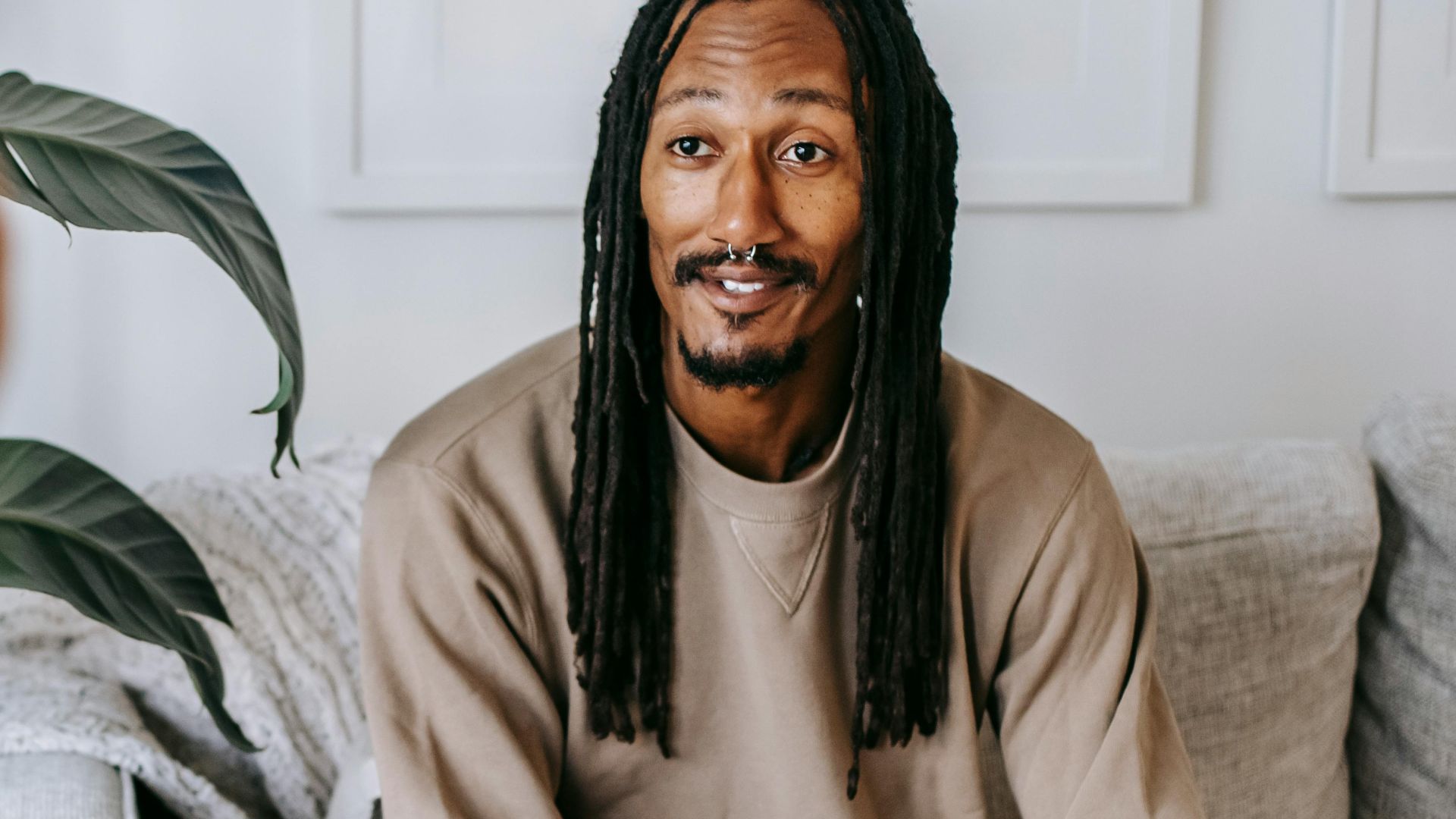 Bearded African American male with dreadlocks and clasped hands speaking with crop anonymous female beloved at home