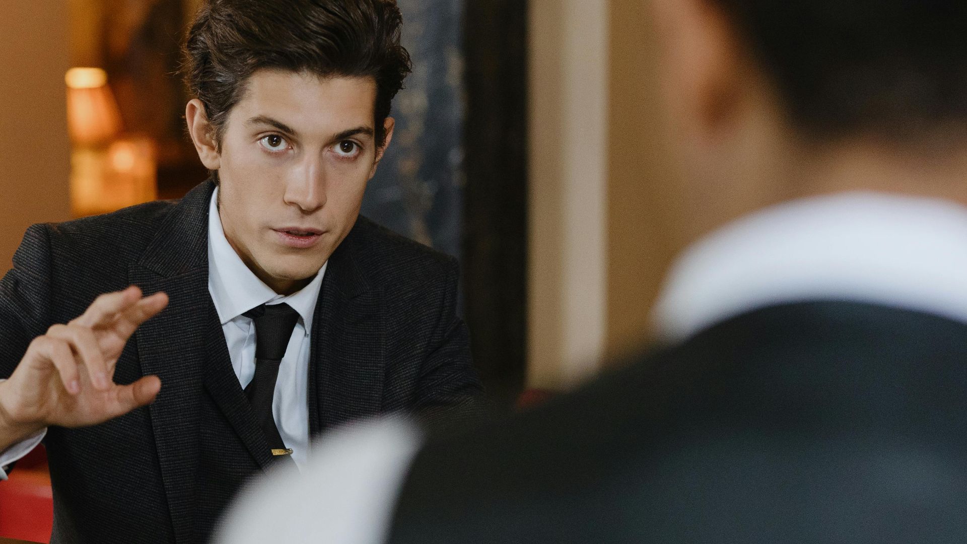 A classy interaction between a gentleman and a waiter at a stylish vintage bar setting.