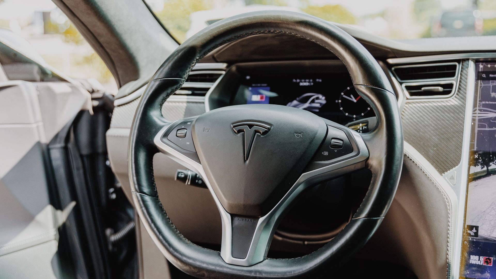 Modern Tesla car interior showcasing futuristic steering wheel design and high-tech dashboard.