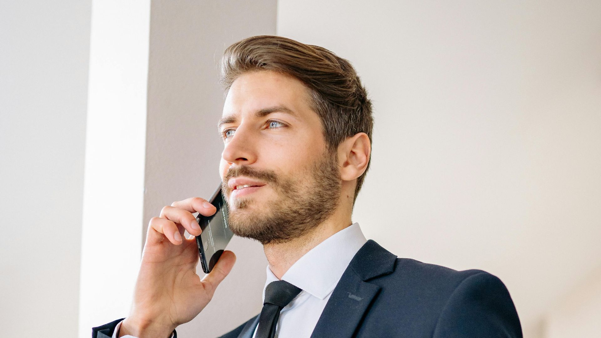 Confident businessman in a suit having a phone conversation indoors.