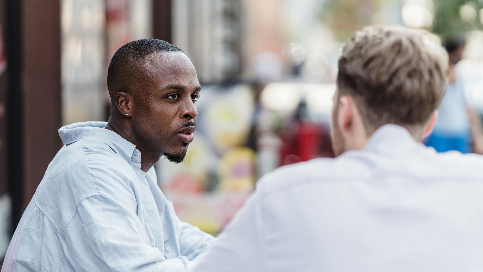 Two men having a conversation in an outdoor setting on a sunny day.