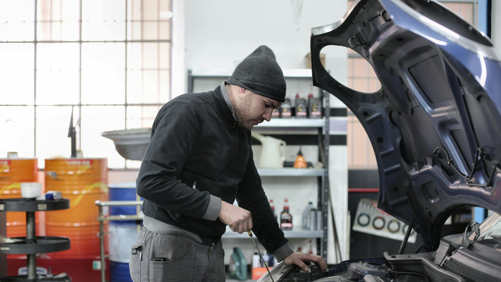 Mechanic checking a car engine in a garage, ensuring quality maintenance and repair.