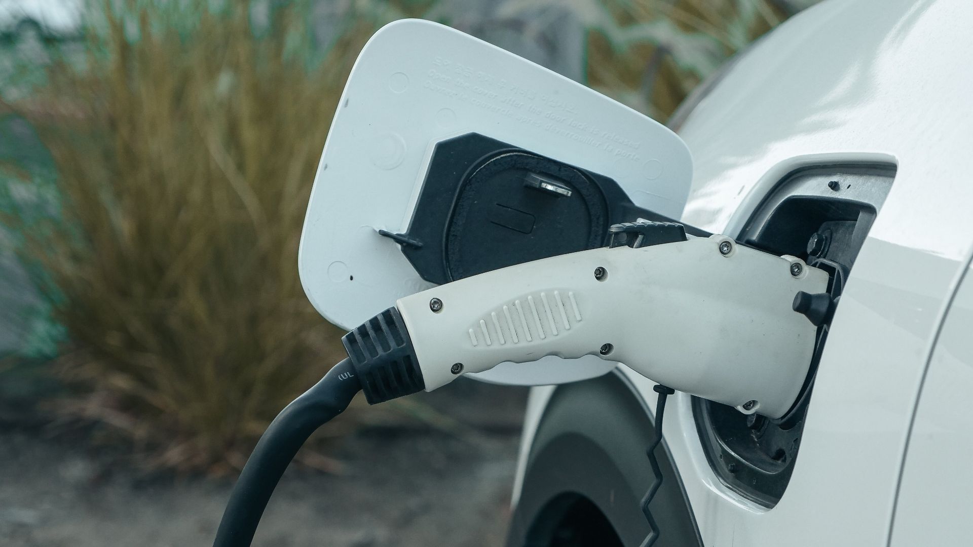 Close-up of electric vehicle connected to charging station outdoors.