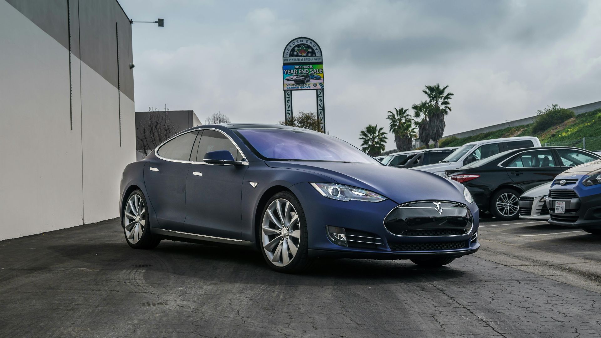 A sleek navy blue Tesla Model S electric vehicle parked in an urban setting.