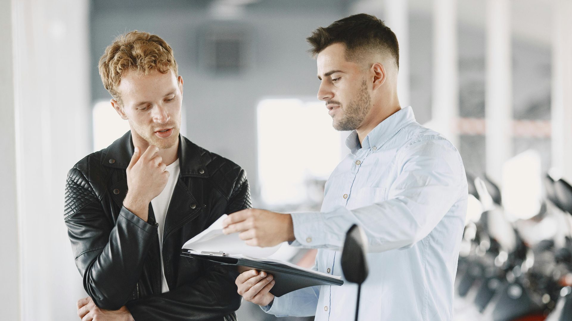 Two adults discussing purchasing options at a motorcycle dealership.
