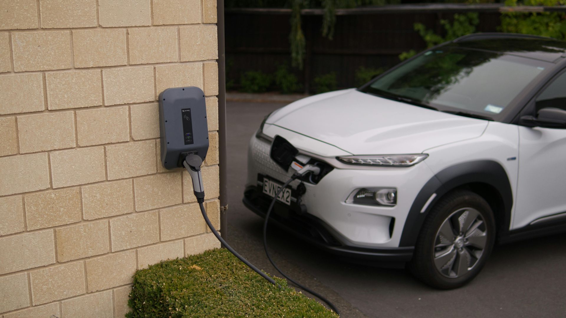 A white electric car charging at a station in Christchurch, New Zealand, showcasing modern eco-friendly transportation.