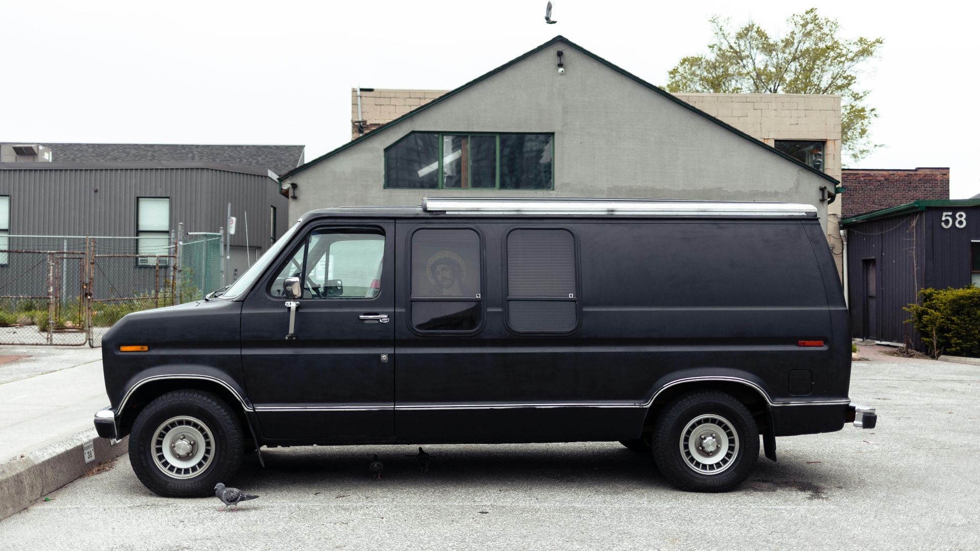 A classic black van parked in an urban setting in Toronto, Canada, highlighting urban architecture.