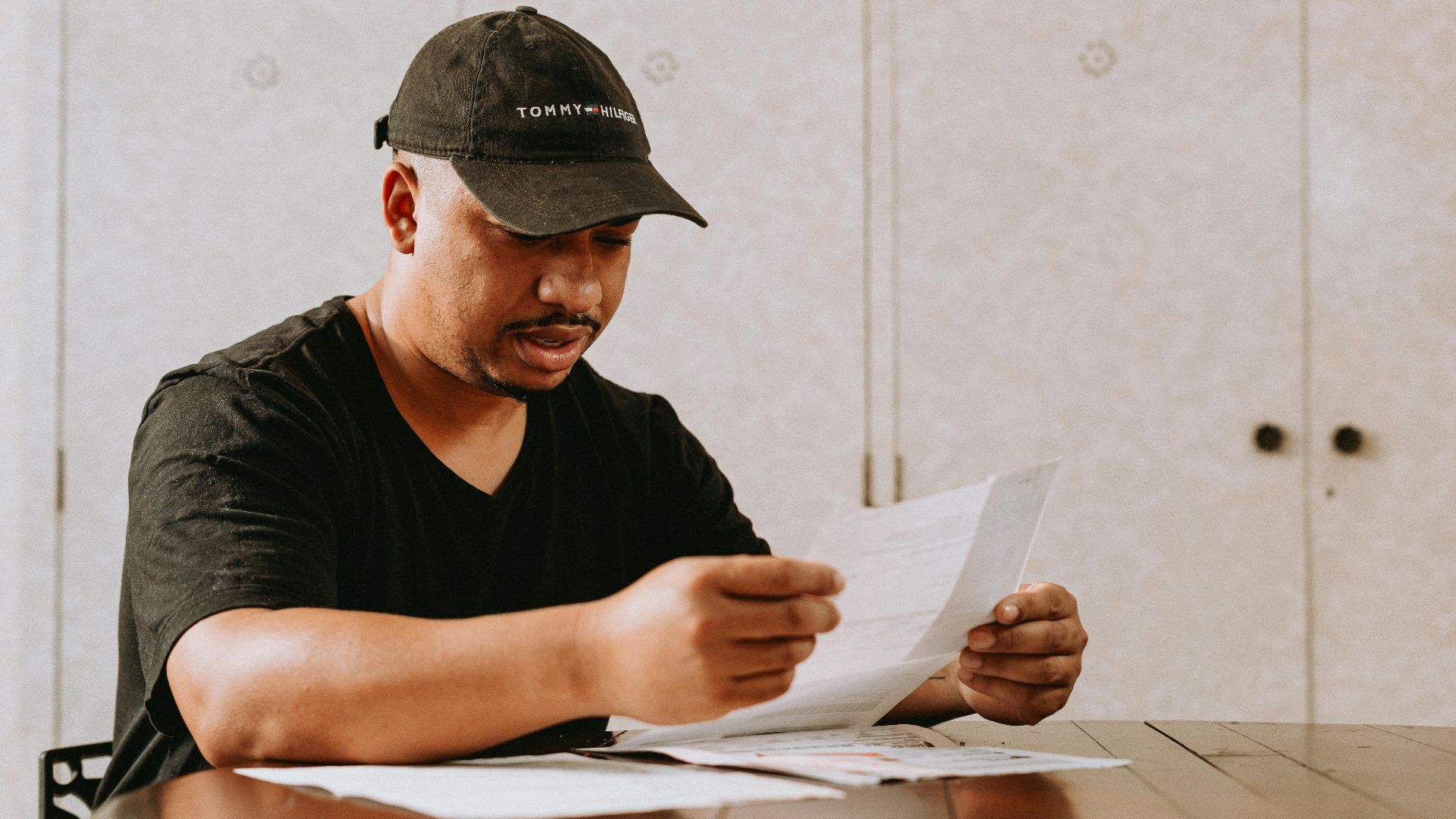 Adult man sitting at home table, focused on reviewing important documents.